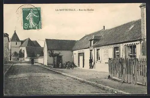AK La Motte-Tilly, Rue des Écoles avec bâtiments et église en arrière-plan