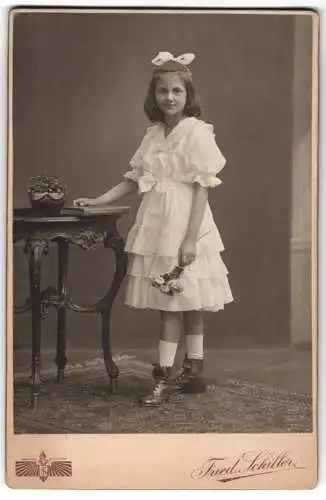 Fotografie Friedr. Schiller, Wien, Mariahilferstrasse 107, hübsches Mädchen Hilde mit Haarschleife am Tisch