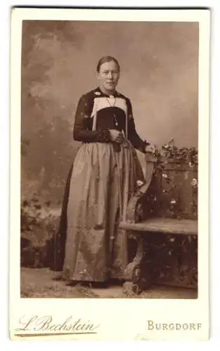 Fotografie L. Bechstein, Burgdorf, Bahnhofstrasse, Frau in traditioneller Kleidung neben Blumendekor