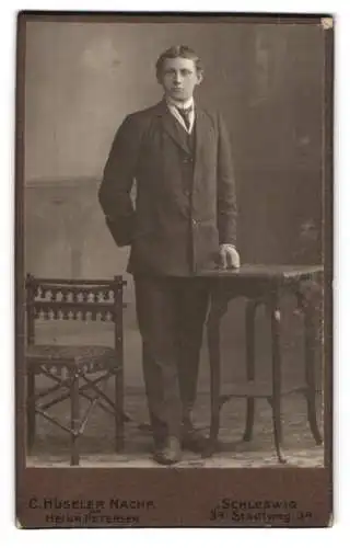 Fotografie C. Hüseler Nachf., Schleswig, Stadtweg 34, Eleganter Herr neben Tisch