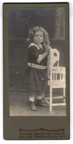Fotografie Samson & Co, Bielefeld, Niedernstr. 26, Kind im Kleid mit Stuhl