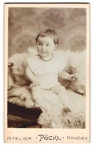 Fotografie Atelier Pöckl, München, Kaufingerstr. 21, Porträt eines kleinen Kindes auf Fell