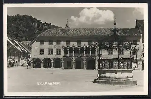 AK Bruck a. d. Mur, Strassenpartie mit Geschäften und Brunnen