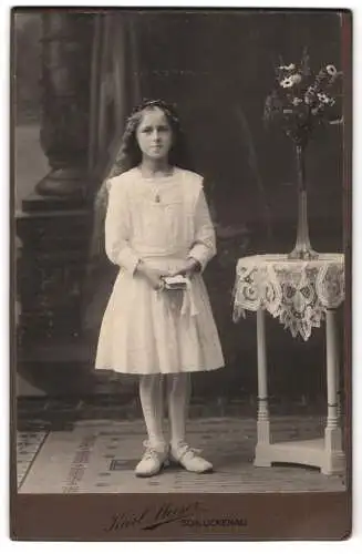 Fotografie Karl Meiser, Schluckenau, Mädchen in weissem Kleid neben Tisch mit Blumen