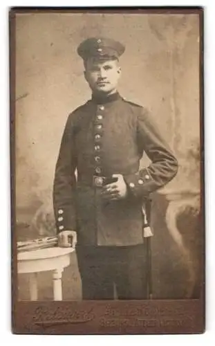 Fotografie P. Seiwert, Salzburg, Atelier Victoria, Soldat in Uniform mit Bajonett, Portepee und Schirmmütze