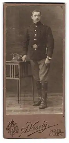 Fotografie A. Veselý, Plzen, Königsquai 5, Soldat in Uniform mit Bajonett und Armbanduhr, Mütze mit Kappenabzeichen
