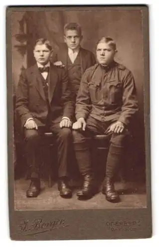 Fotografie J. Berger, Oderberg, Bahnhof, Zwei junge Männer in Anzügen und ein k.u.k. Soldat in Uniform