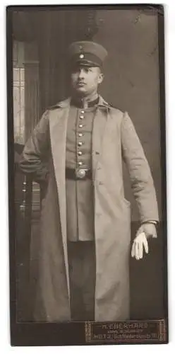 Fotografie H. Eberhard, Metz, St. Medardstr. 10, Uffz. in Uniform mit Mantel und Schirmmütze