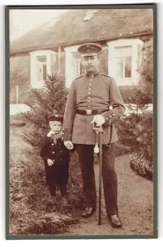 Fotografie unbekannter Fotograf und Ort, Vize-Feldwebel in Uniform mit Säbel, mit Kind im Garten