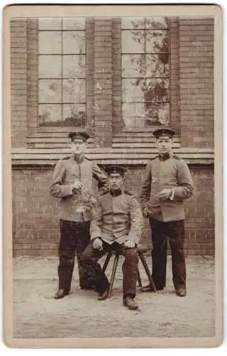 Fotografie unbekannter Fotograf und Ort, Ort unbekannt, drei Soldaten in Uniform mit Schirmmützen