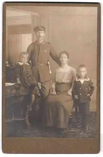 Fotografie unbekannter Fotograf und Ort, Porträt einer Familie, Uffz. in Uniform mit Bajonett und Feldspange, Posen 1917