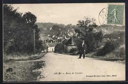 AK Arces, Route de Cerisiers avec vue sur le village et un homme sur le chemin