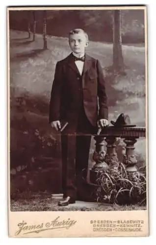 Fotografie James Aurig, Dresden, junger Knabe im Anzug vor einer Studiokulisse
