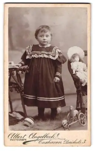 Fotografie Albert Angelbeck, Cuxhaven, Deichstrasse 3, Kind mit Spielzeug und Puppe und Figur auf Rädern