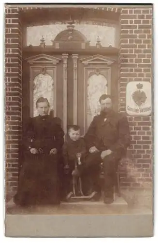Fotografie unbekannter Fotograf und Ort, Familie vor verzierten Türendes Gemeinde-Vorsteher mit Schaukelpferd