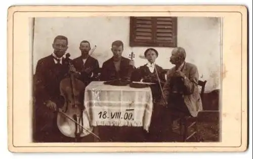 Fotografie unbekannter Fotograf und Ort, Musikerensemble mit Instrumenten um einen Tisch, 1900