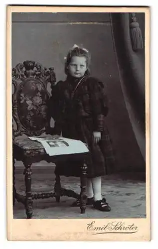 Fotografie Emil Schröter, Jüterbog, Kind im karierten Kleid neben Stuhl