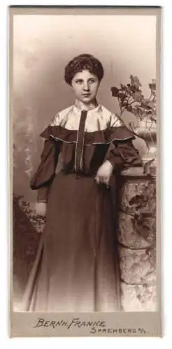 Fotografie Bernh. Franke, Spremberg /N. L., Frau mit elegantem Kleid neben Pflanzendekoration