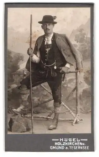 Fotografie Fritz Hugel, Holzkirchen, Mann in traditioneller Tracht mit Wanderstab, Lederhose