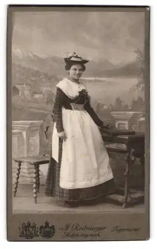 Fotografie J. Reitmayer, Tegernsee, Hauptstrasse 13, Frau in Tracht vor malerischem Hintergrund