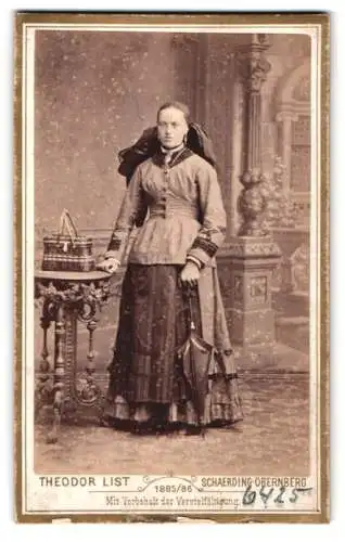 Fotografie Theodor List, Schärding a. Inn, Schlossgasse 5, Stehende Dame in Tracht mit Korb auf dem Tisch