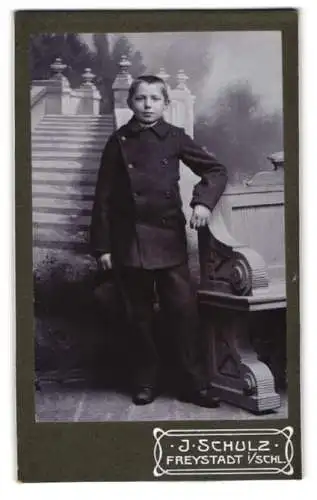Fotografie J. Schulz, Freystadt, Glogauer Strasse 142, Junge mit Hut neben dekorativer Kulisse