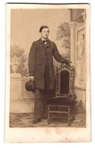 Fotografie unbekannter Fotograf und Ort, eleganter Herr mit Hut neben verziertem Stuhl