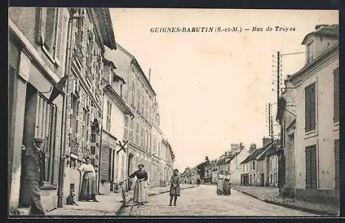 AK Guignes-Rabutin /S.-et-M., Rue de Troyes animée avec passants et bâtiments historiques
