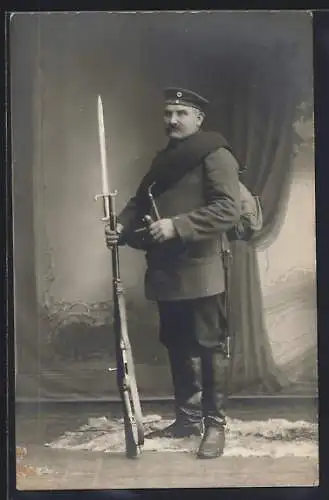 Foto-AK Soldat in Uniform mit Pfeife, Gewehr mit Bajonett
