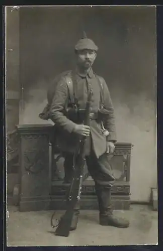 Foto-AK Soldat in Feldgrau Uniform mit Marschausrüstung, Pickelhaube und Gewehr