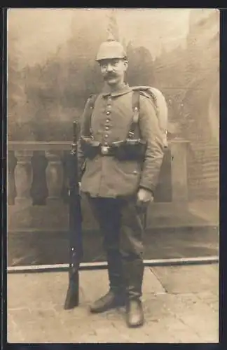 Foto-AK Soldat in Feldgrau Uniform mit Pickelhaube und Gewehr