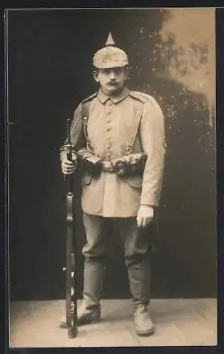 Foto-AK Soldat in Feldgrau Uniform mit Pickelhaube und Gewehr