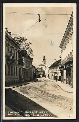 AK Bruck a. d. Leitha, Kaiser Franz Josefstrasse mit Geschäften und Kirche