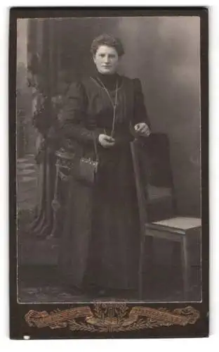 Fotografie M. Rutschmann, Rotthalmünster, Frau in dunklem Kleid mit Stuhl
