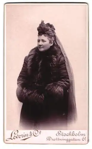 Fotografie Leverin & Co, Stockholm, Drottninggatan 61, Frau in elegantem Mantel mit Pelzbesatz, Muff