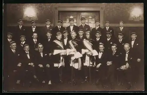 Foto-AK Studenten mit Mützen, Degen und Schärpen in einem Festsaal, Gruppenfoto