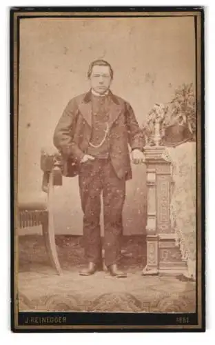Fotografie J. Reinegger, Lambach, Herr im Anzug mit dekorativem Tisch 1882