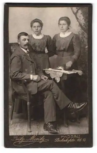 Fotografie Fritz Moritz, Passau, Bahnhofstrasse 66, Porträt eines sitzenden Mannes und zwei stehenden Frauen