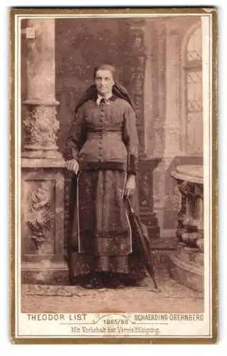 Fotografie Theodor List, Schärding, Schlossgasse 5, Frau mit Schirm neben Säule