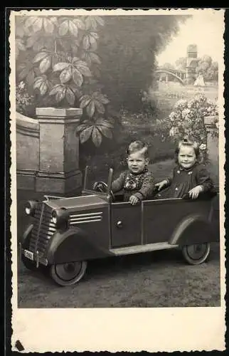 Fotografie Spielzeug Auto / Tretauto, Kinder in Auto-Draisine sitzend