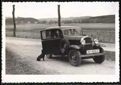 Fotografie Auto Opel, Hund sitzt neben PKW mit Kennzeichen Provinz Westfalen IX-62913
