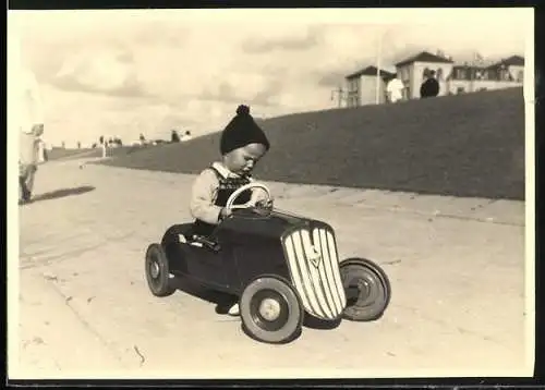 Fotografie Spielzeug Auto, Knabe mit Pudelmütze im Tretauto - Draisine - Seifenkiste