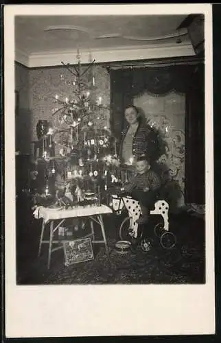 Foto-AK Familie neben einem Weihnachtsbaum, Junge mit Spielzeugpferd