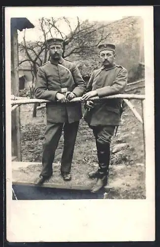 Foto-AK Zwei Soldaten an einem Zaun, Uniformfoto