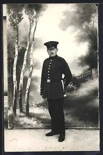 Foto-AK Soldat mit Schirmmütze vor Fotokulisse, Uniformfoto
