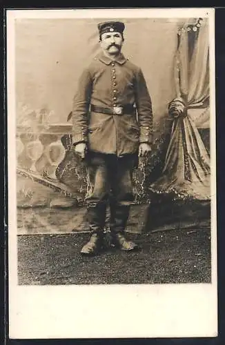 Foto-AK Soldat vor Fotokulisse im Freien, Uniformfoto