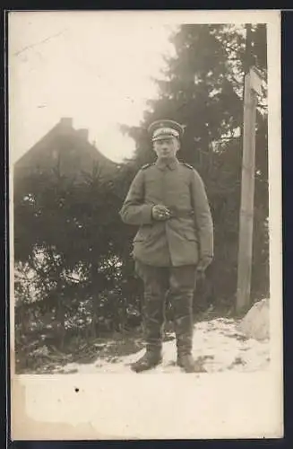 Foto-AK Soldat mit Schirmmütze u. Zigarette im Winter, Uniformfoto