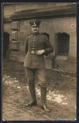 Foto-AK Soldat mit Schirmmütze vor einem Gebäude, Uniformfoto