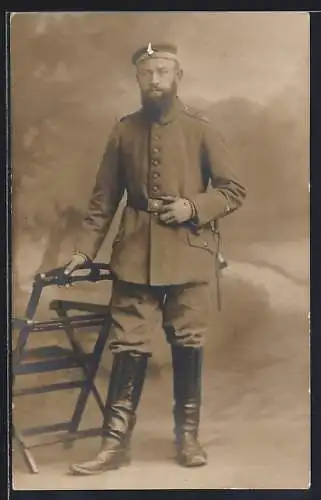 Foto-AK Soldat mit Vollbart vor einer Fotokulisse, Uniformfoto