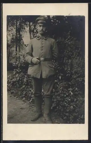 Foto-AK Soldat mit Schirmmütze im Freien, Uniformfoto